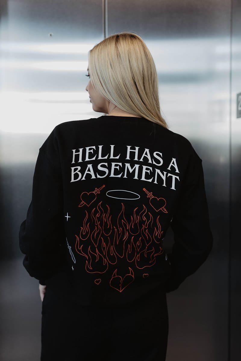 The back of the black crewneck reading HELL HAS A BASEMENT above a red flame graphic