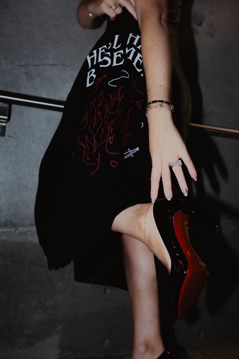 Detail of the HELL HAS A BASEMENT crewneck worn with red-soled heels