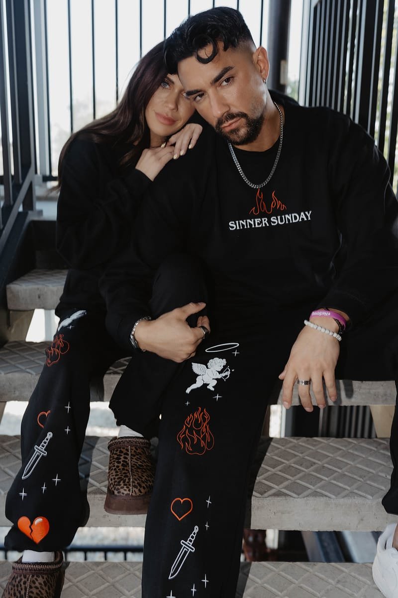 A couple seated in Sinner Sunday crewnecks and cherub sweatpants